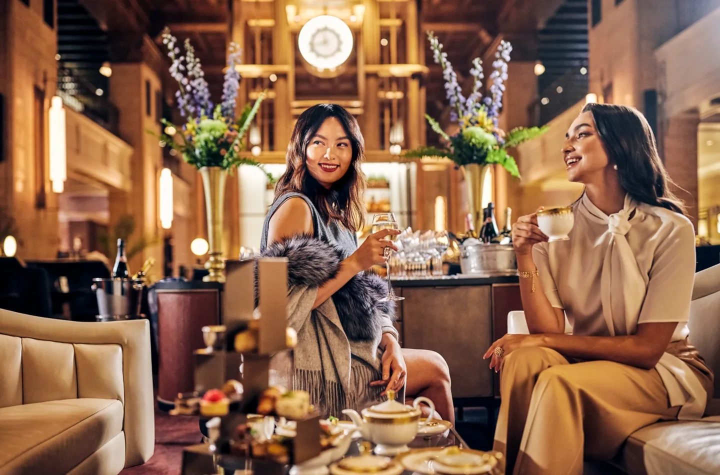 Two women sharing afternoon tea beneath the clock at Fairmont Royal York