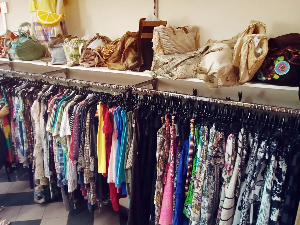 A woman browsing tightly packed clothing racks in a thrift shop