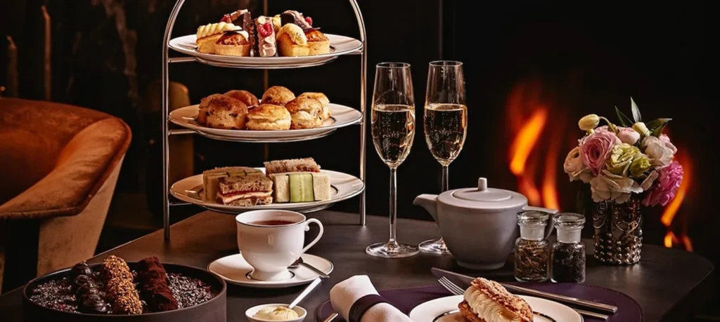 A tiered afternoon tea stand with scones, sandwiches, pastries and teacups at EPOCH