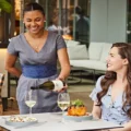 A server pouring wine for two women dining on the EPOCH terrace
