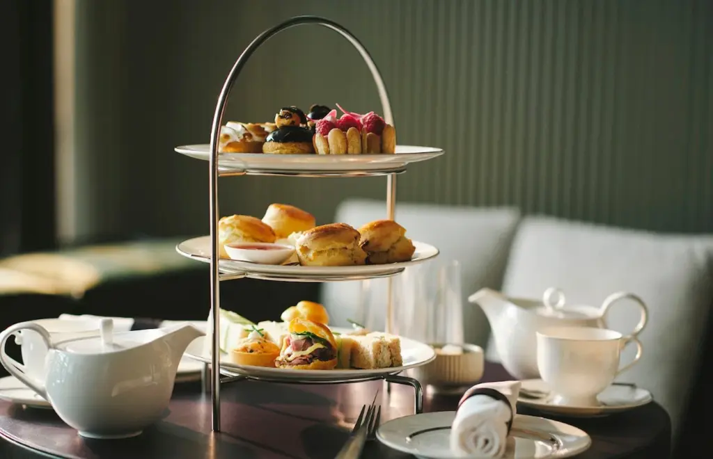 Sandwiches, scones and pastries on a three-tier stand beside a teapot at EPOCH