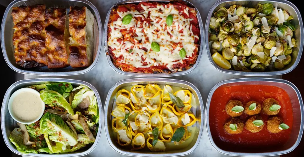 Six plates of plant-forward Italian food arranged on a metal table at Gia in Toronto