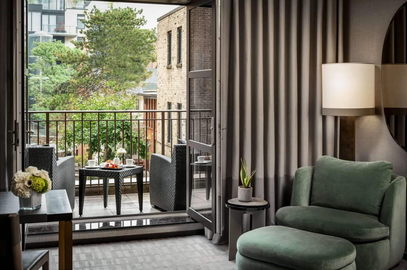 A Hazelton room with a green armchair and an outdoor balcony