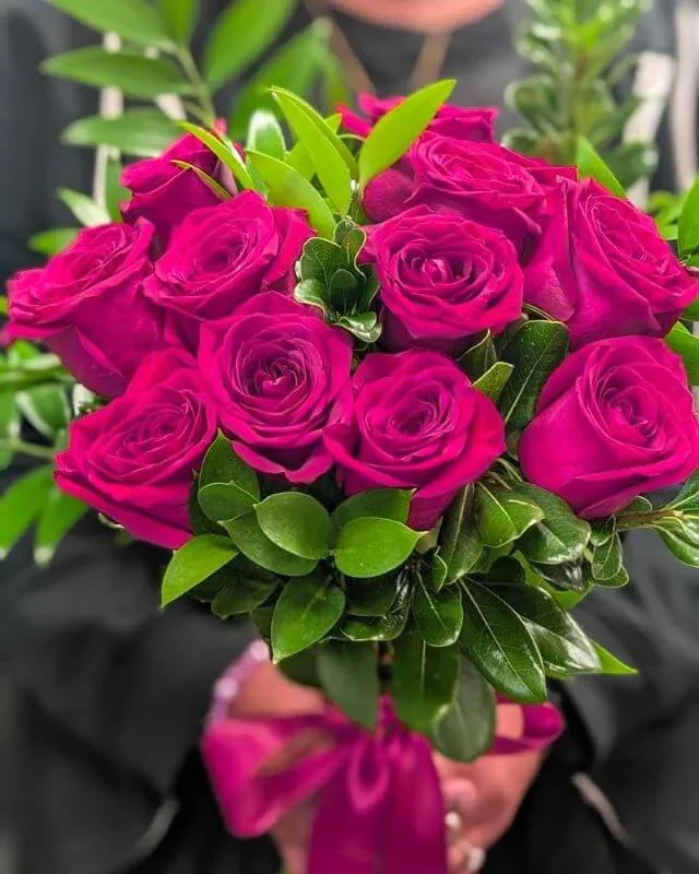 A hand holding a pink rose bouquet from Flower Creations’ catalogue