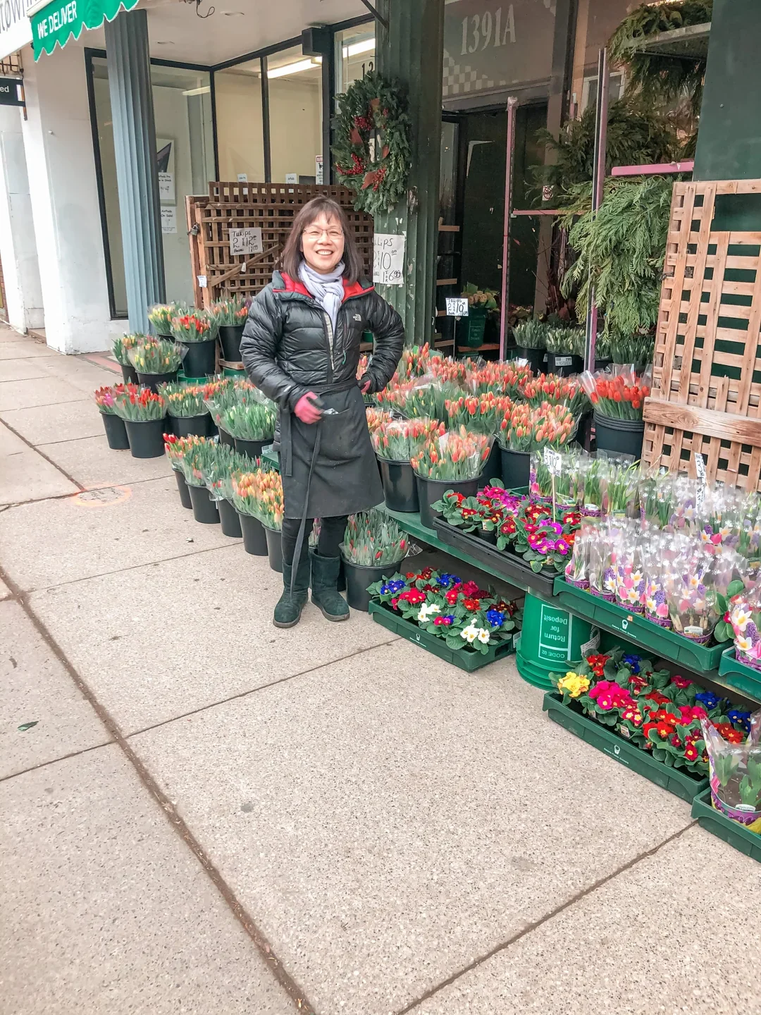 A person standing outside Eden Flower Shop beside buckets of flowers