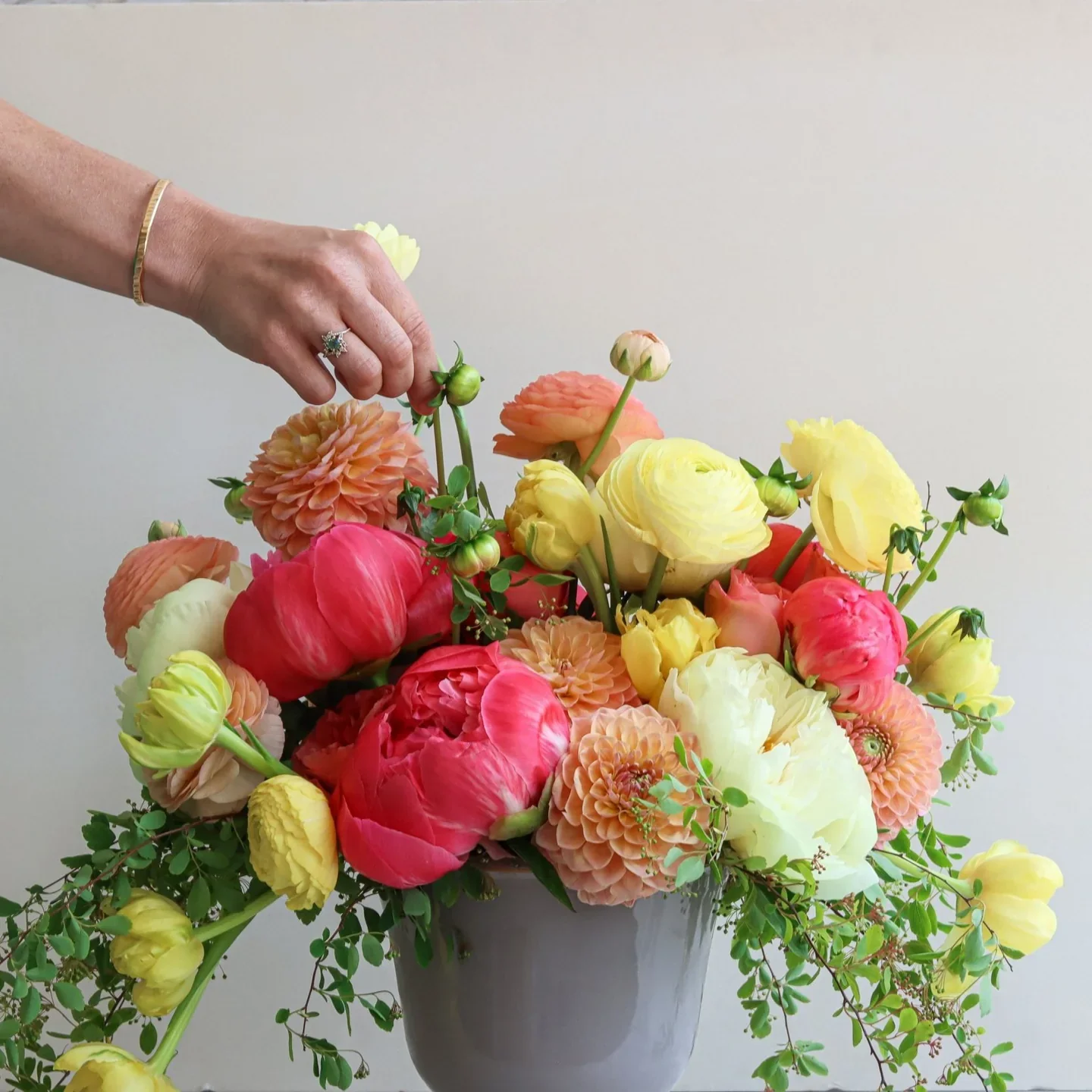 A hand holding a round bouquet of mixed flowers