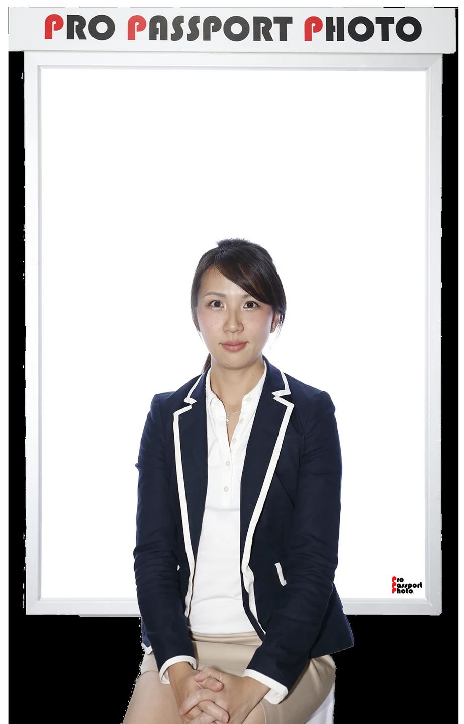 A woman sits in front of a white Pro Passport Photo backdrop