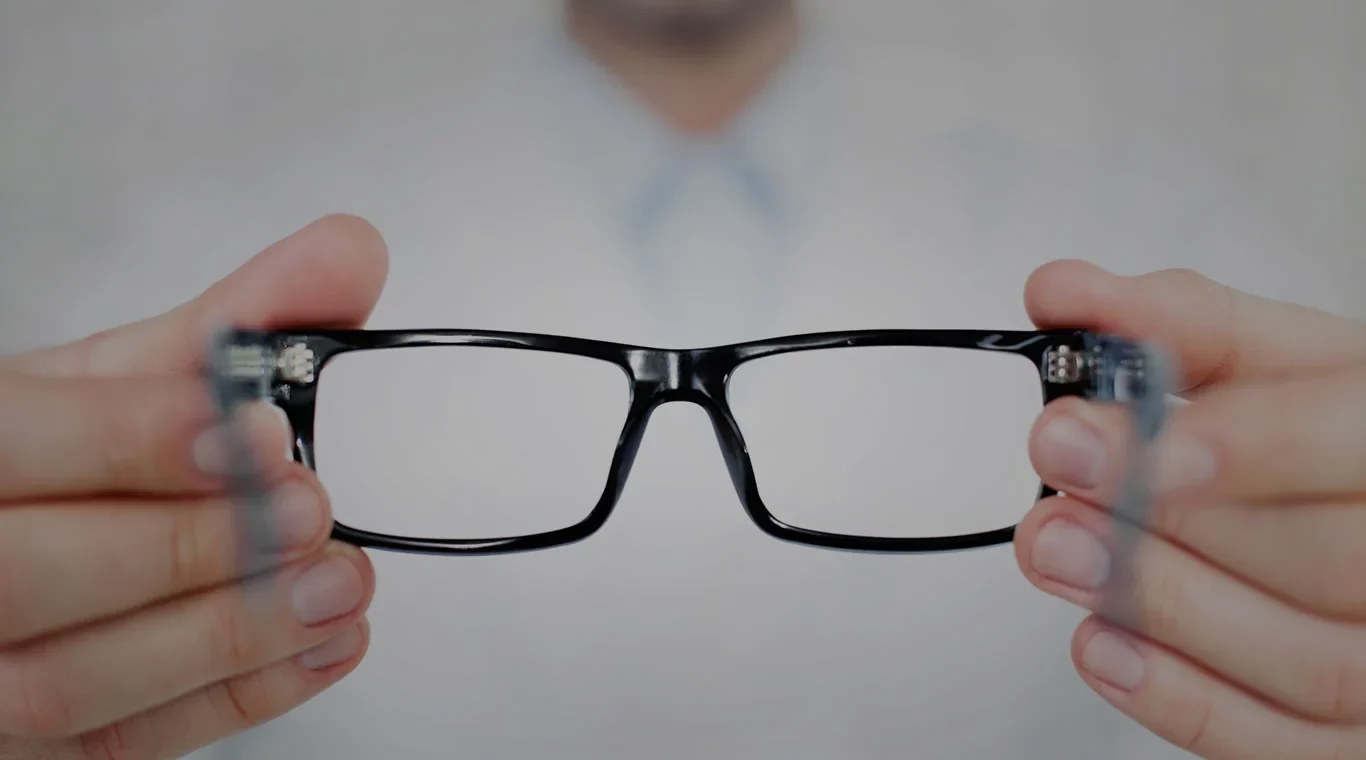 Hands holding a pair of black eyeglasses