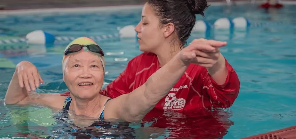 Instructor assisting an adult swimmer at the Miles Nadal JCC