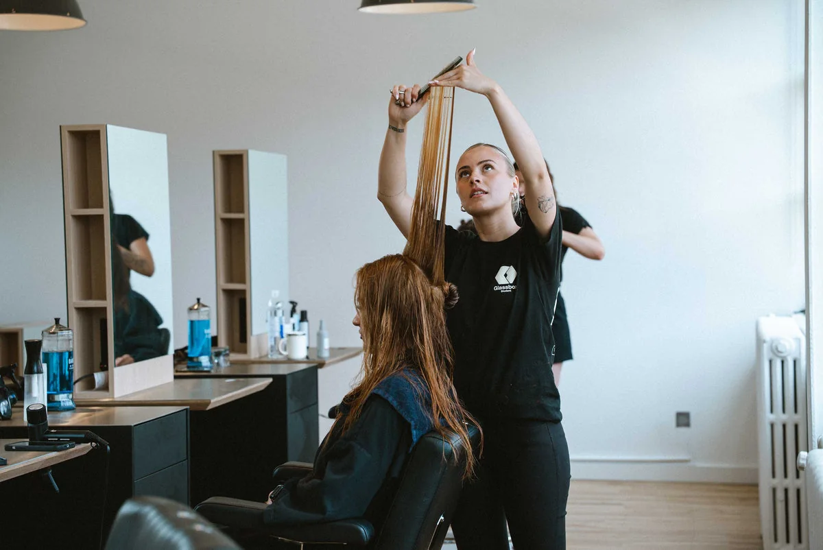 A stylist lifting a section of hair during a haircut at Glassbox Education.