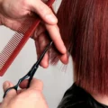Scissors trimming a straight red bob at chin length.