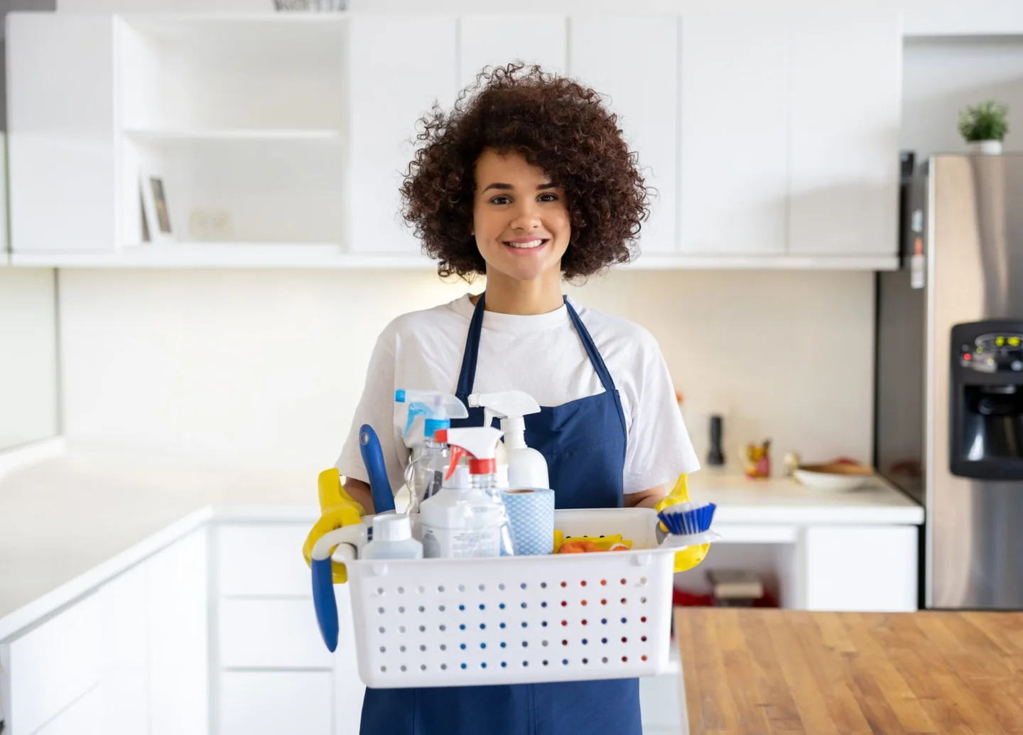 A cleaner holding a basket of brushes, cloths and cleaning products.