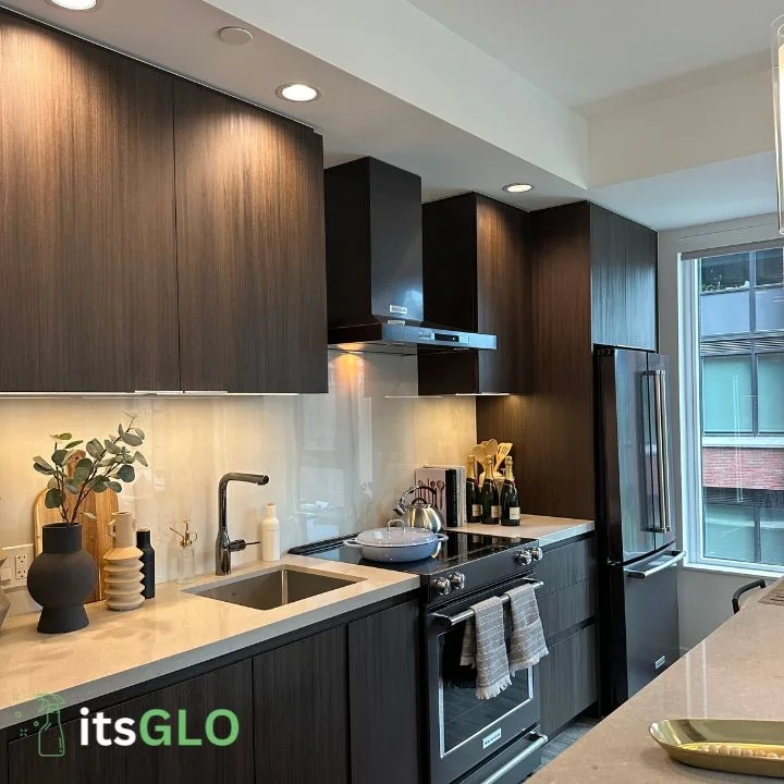 Clean dark kitchen cabinets, a stove and a sink shown by itsGLO.