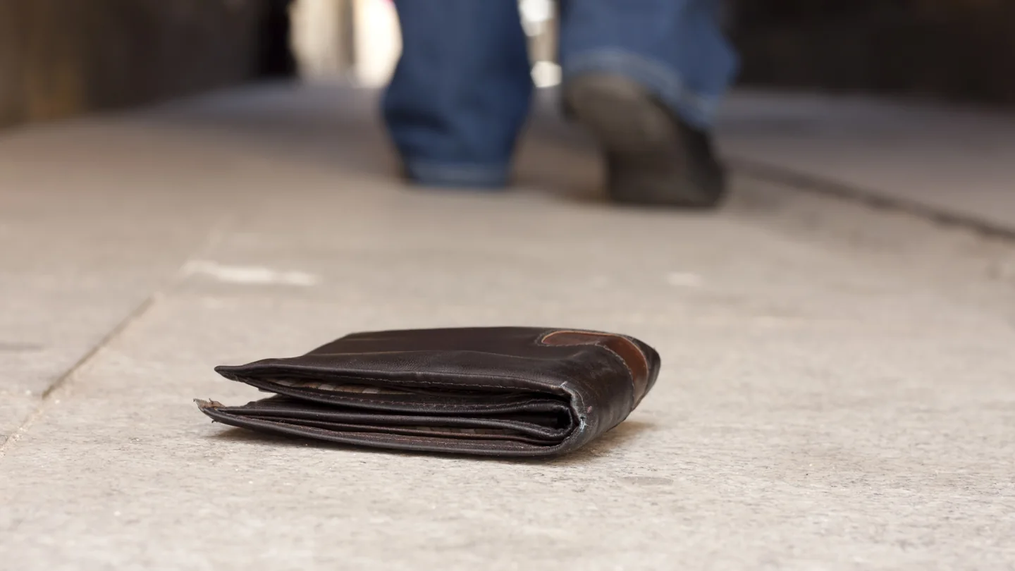 A wallet on the ground as a person walks away
