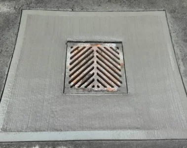A metal catch-basin grate set into a concrete surround