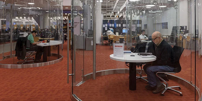 A library customer working in a glass study pod at Toronto Reference Library