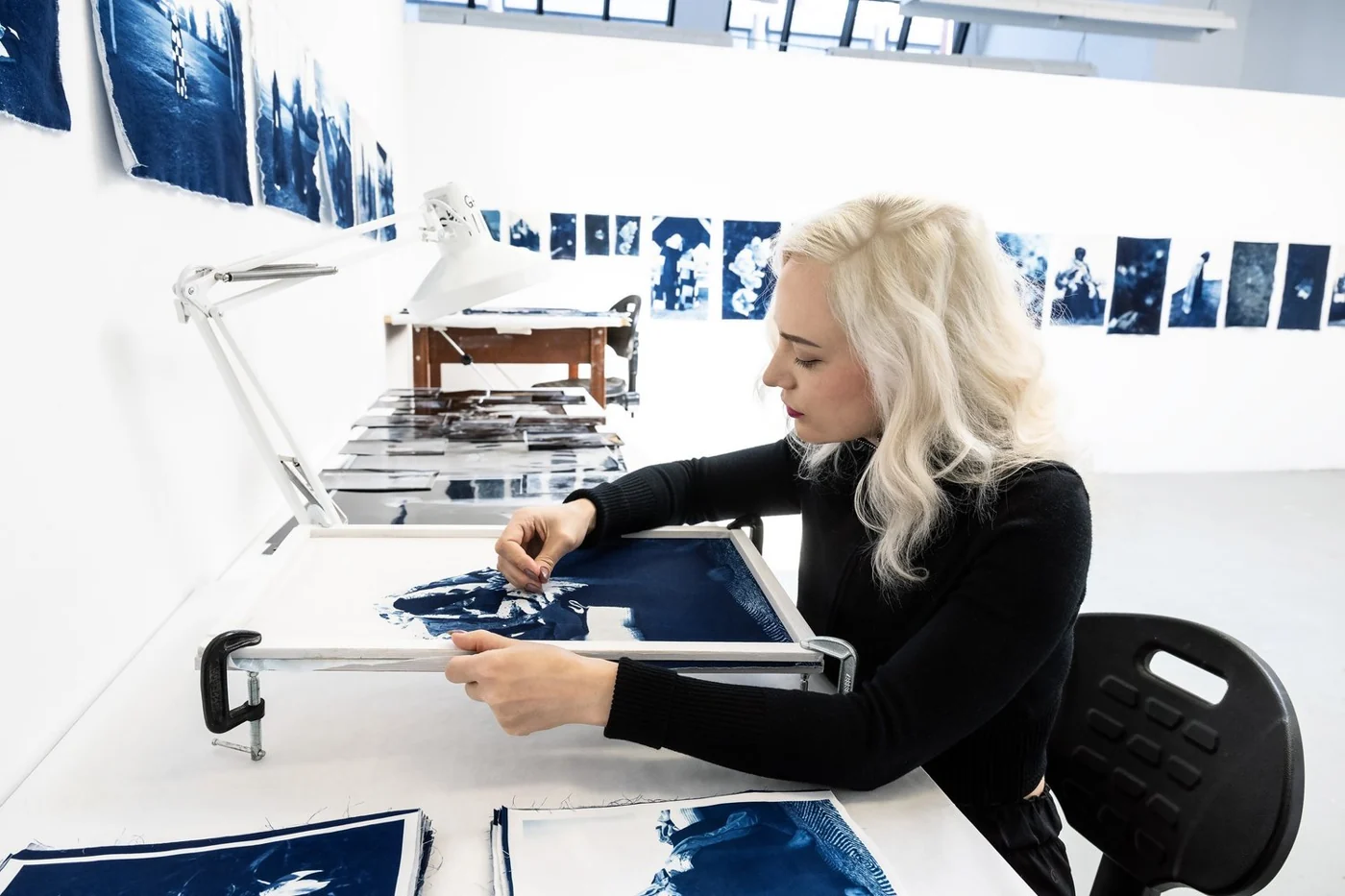 Amber Helene Müller St. Thomas working with blue cyanotype prints in a studio at the Banff Centre