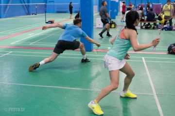 Two players moving across a badminton court at Epic Sports