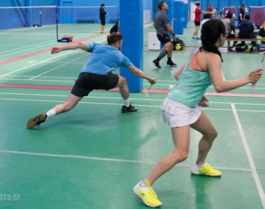 Two players moving across a badminton court at Epic Sports