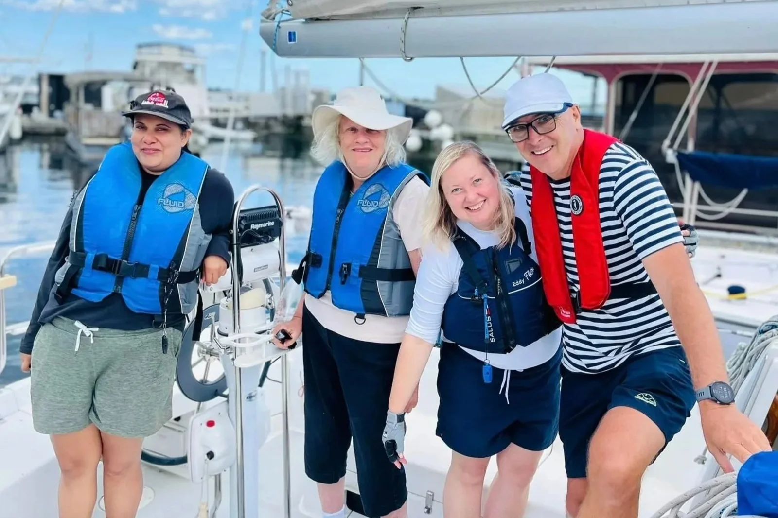 Sailing participants gathered beside a boat at the dock