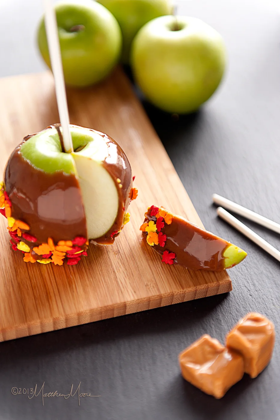 A sliced caramel apple beside wrapped caramels