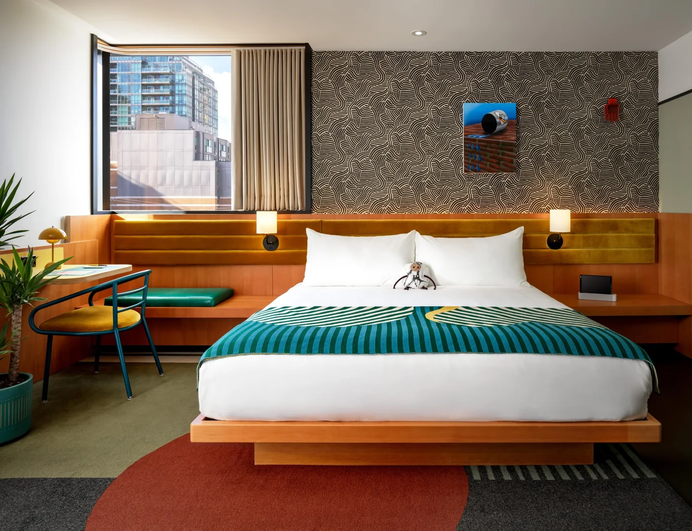 A guest room at The Drake Hotel with art and a green bedcover