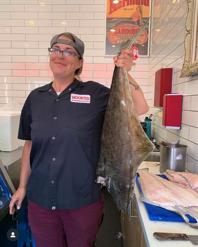 A Hooked staff member holding a large fish