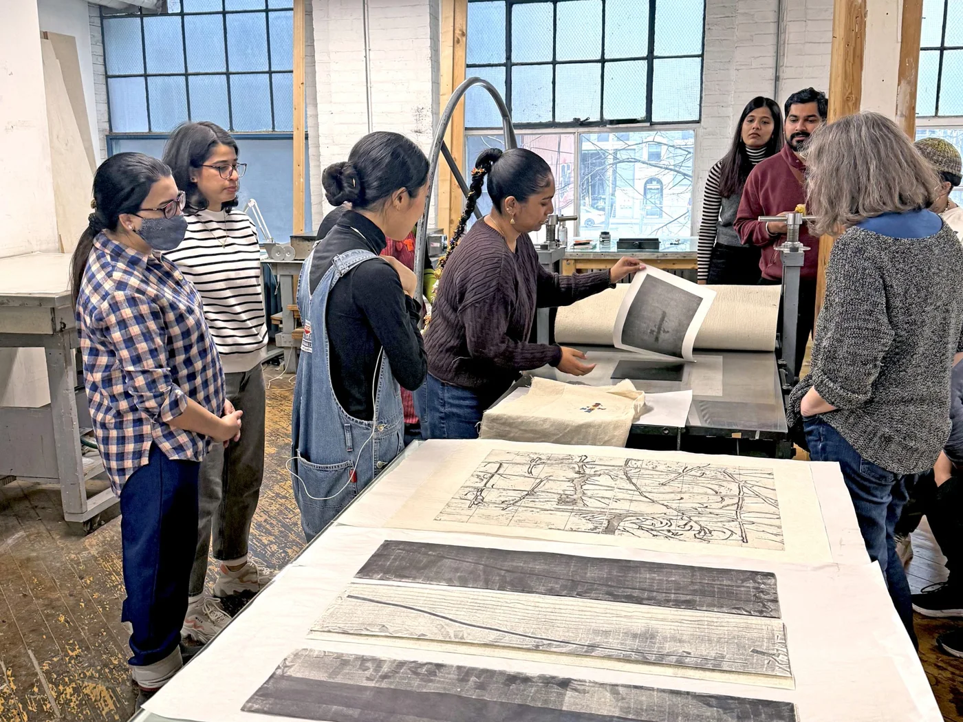 Visitors looking at prints around a table at Open Studio