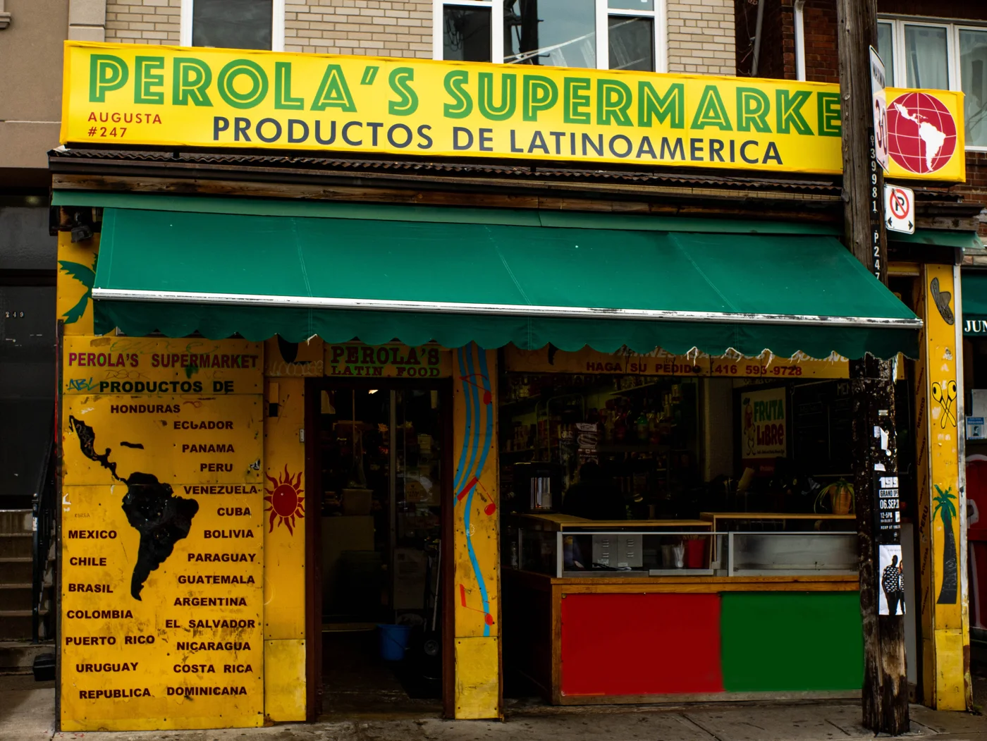 The yellow and green storefront of Perola Supermarket
