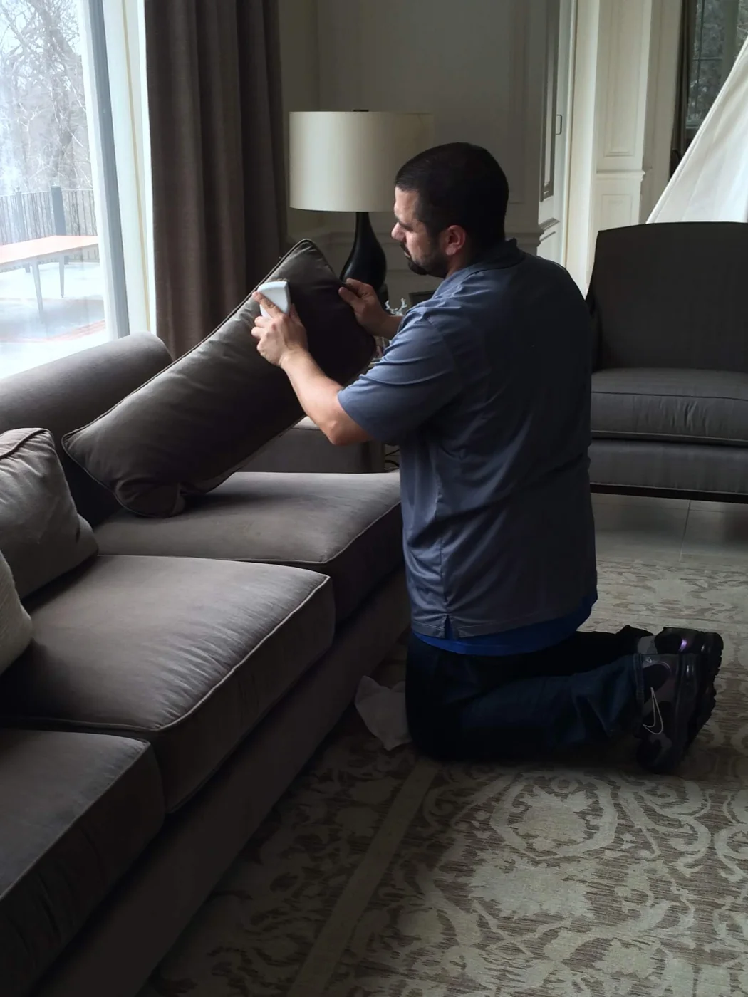 A technician cleaning an upholstered sofa