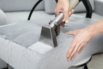An upholstery extraction tool cleaning a fabric sofa