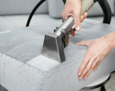 An upholstery extraction tool cleaning a fabric sofa