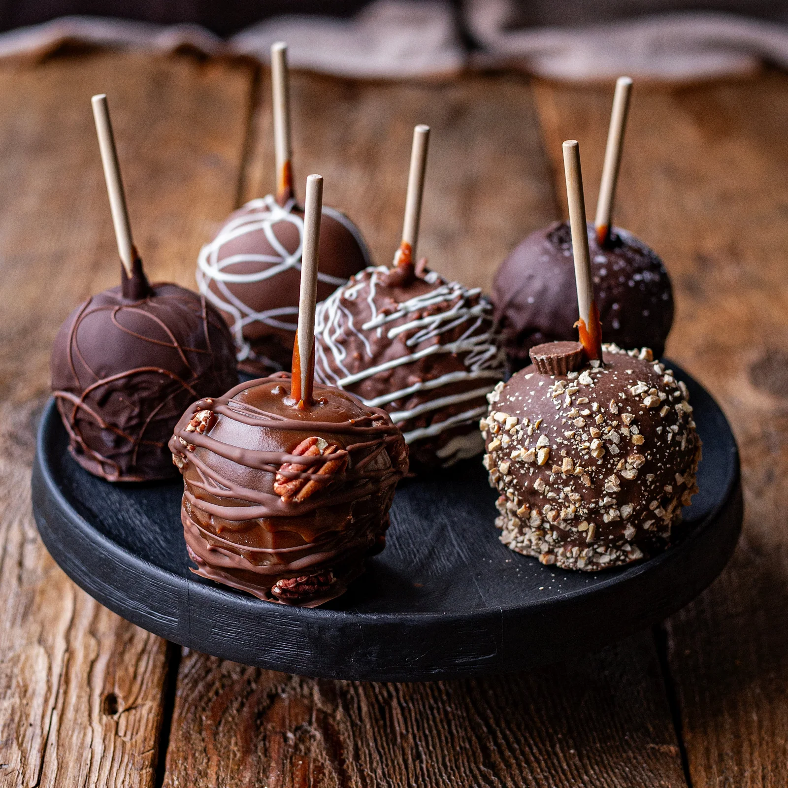 Several decorated caramel apples displayed on a plate