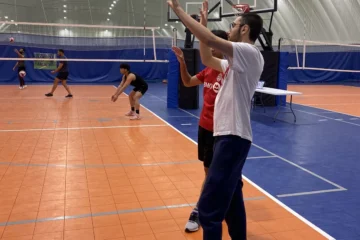 Two players practising volleyball in a gym