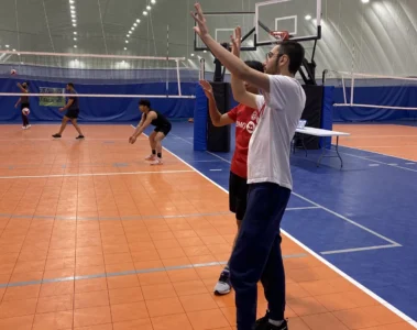 Two players practising volleyball in a gym