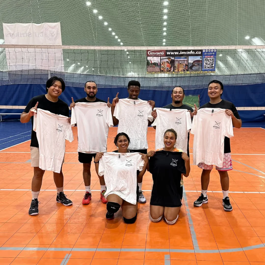 A volleyball team posing together beside the court