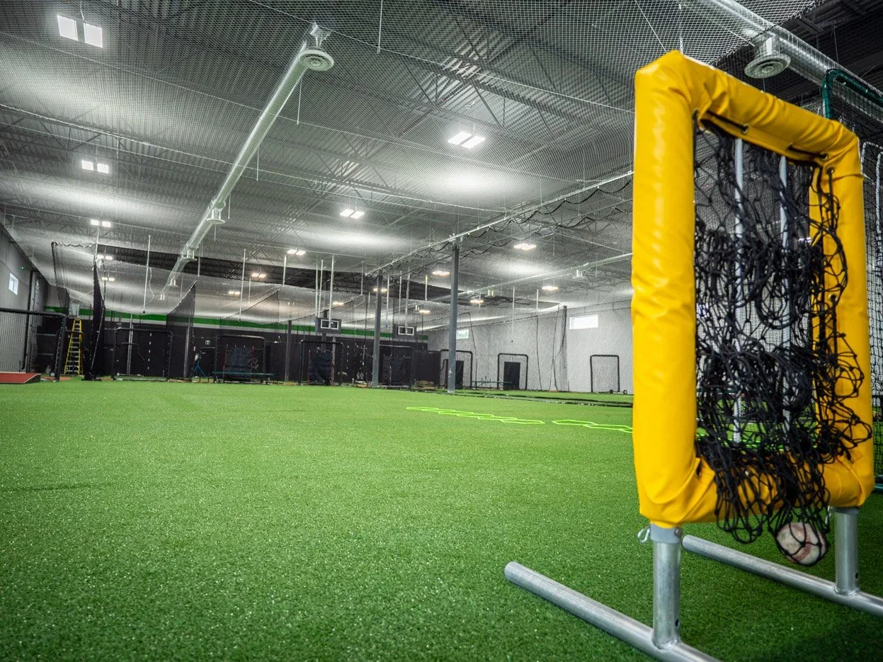 An L-shaped protective screen stands inside an indoor training lane