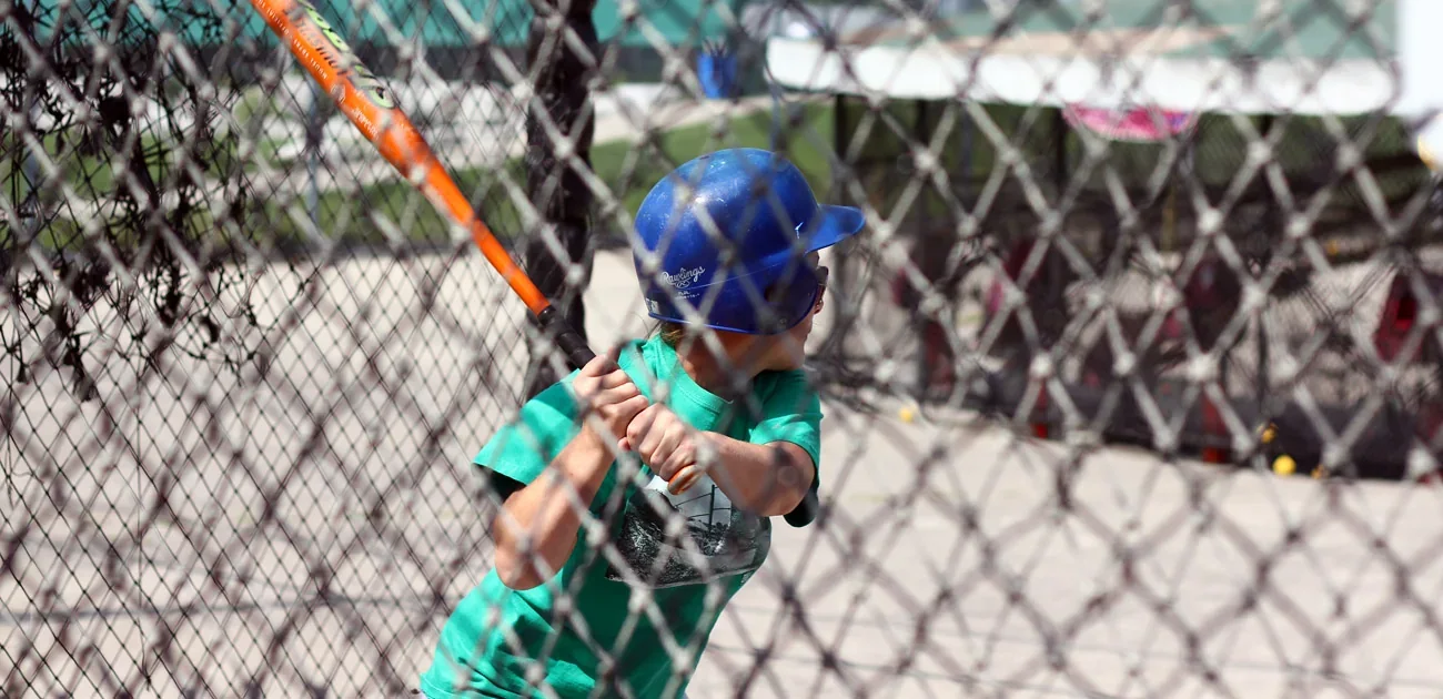 A young batter swings inside an outdoor cage at Pickering Playing Fields