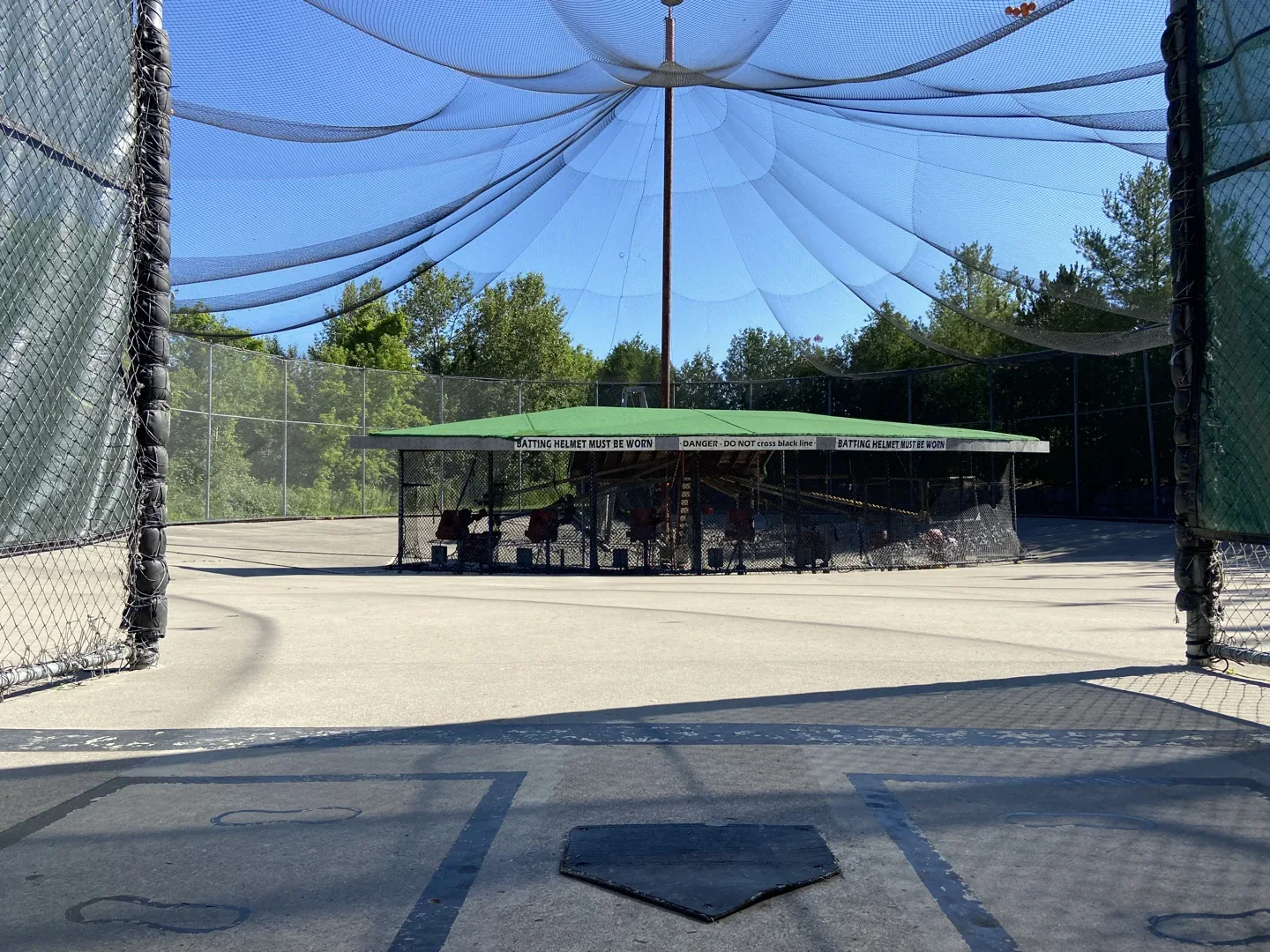 Outdoor netted batting lanes face pitching machines at Timber Creek