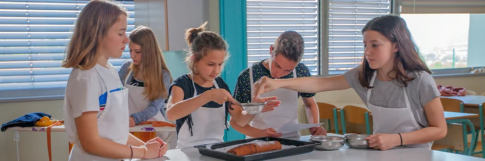 A teacher guides young participants during a cooking activity