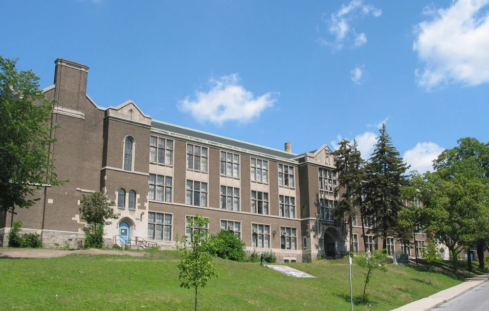 The brick exterior of Western Technical-Commercial School beside a grassy slope
