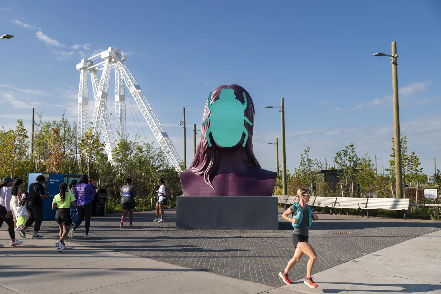 Visitors stand beside a large face-shaped sculpture near the Atlas Crane