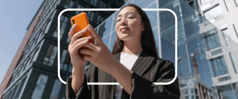 A woman uses an orange phone outside a modern building