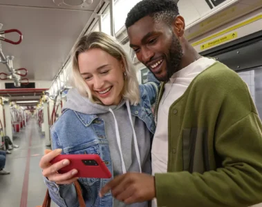 Two riders look at a phone inside a TTC subway train