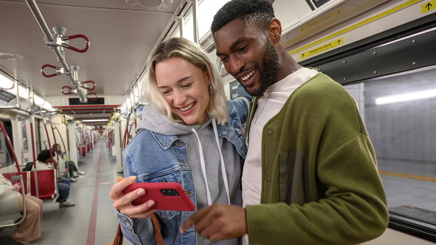 Two riders look at a phone inside a TTC subway train