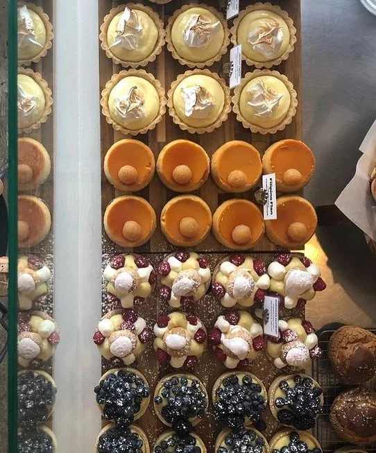 A glass display case containing individual cakes and pastries at Bakerbots