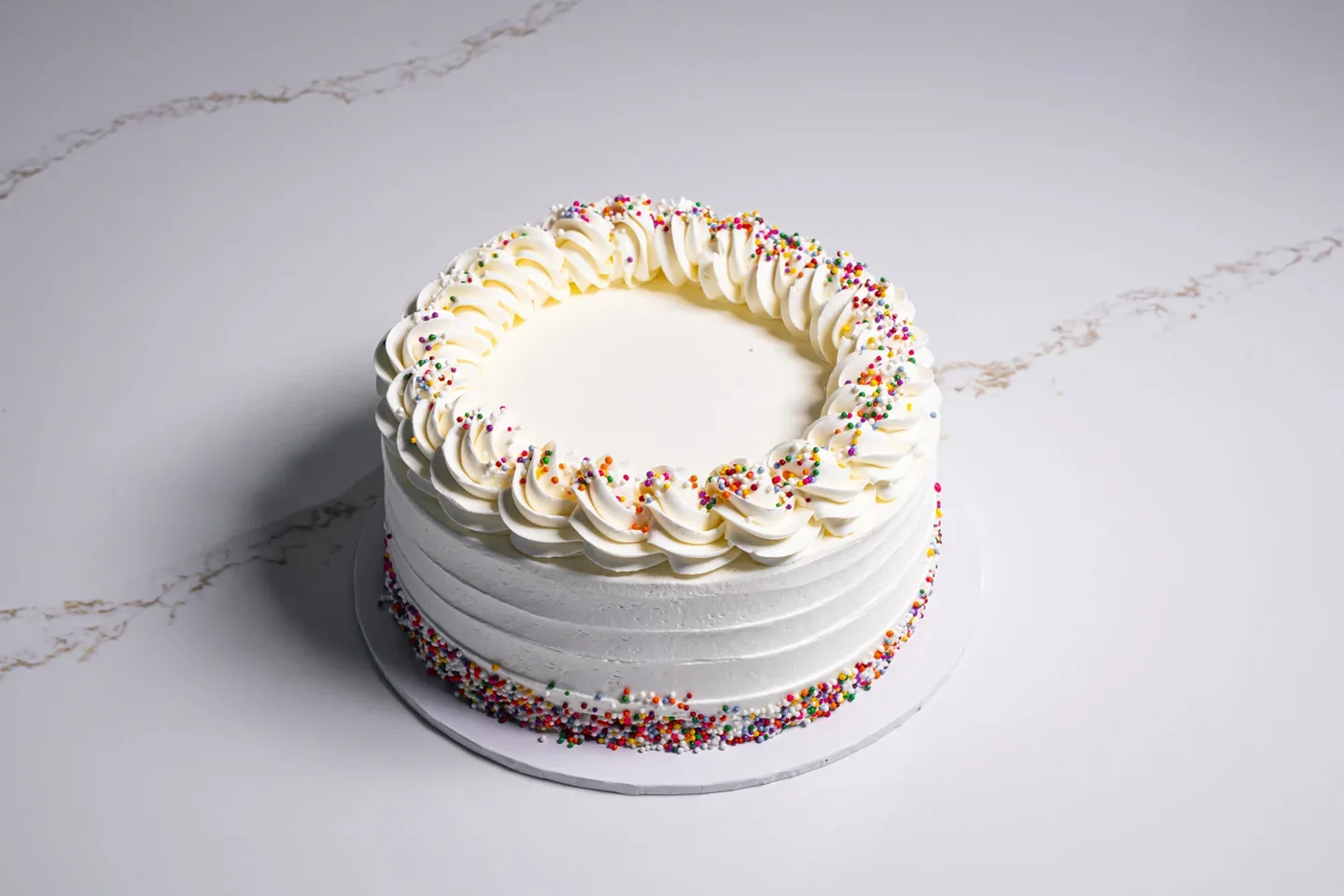Caldense’s white confetti cake with piped edging and rainbow sprinkles
