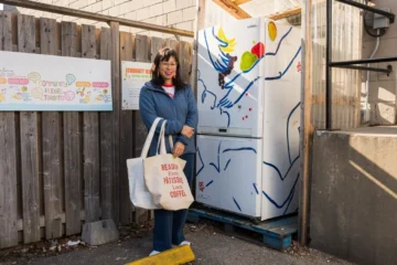 Pay Chen stands with shopping bags beside the painted community fridge on Adelaide Street West