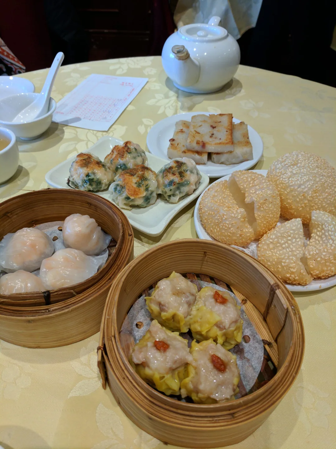 Several dim sum baskets, a teapot and an order slip on a table at Dim Sum King