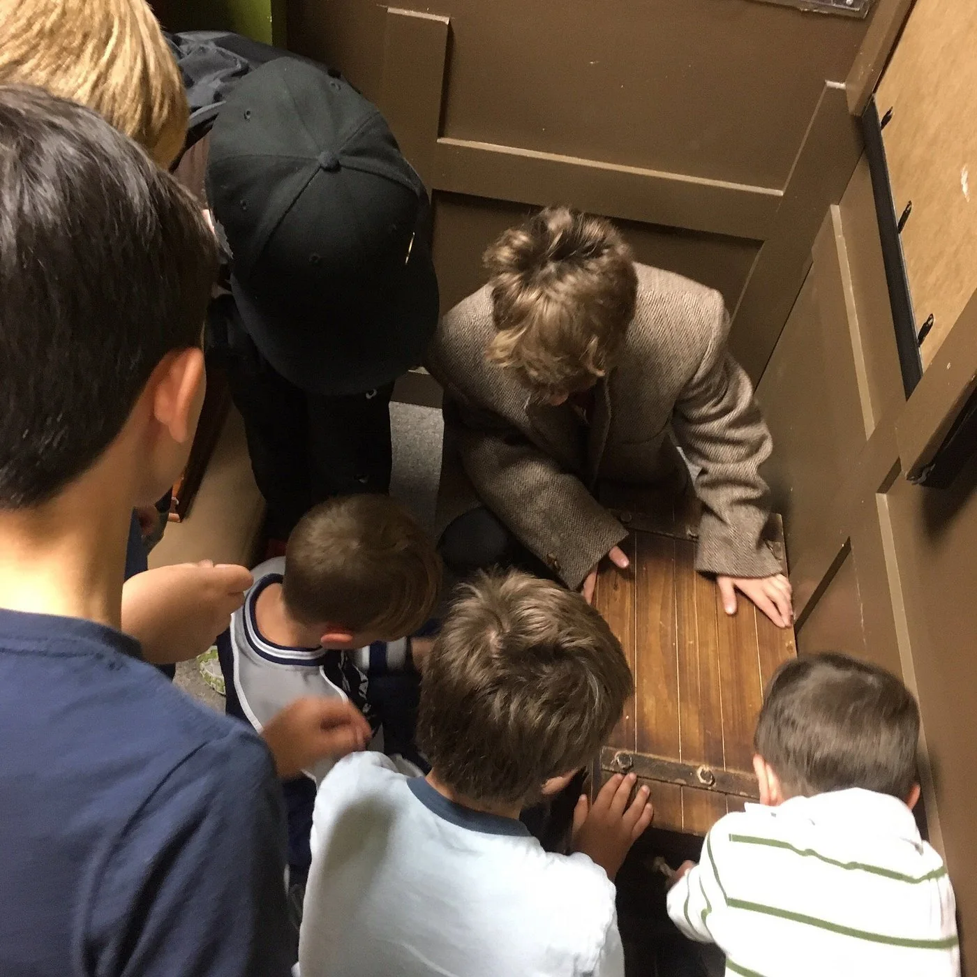 A group works together around a low puzzle at Looking Glass Adventures